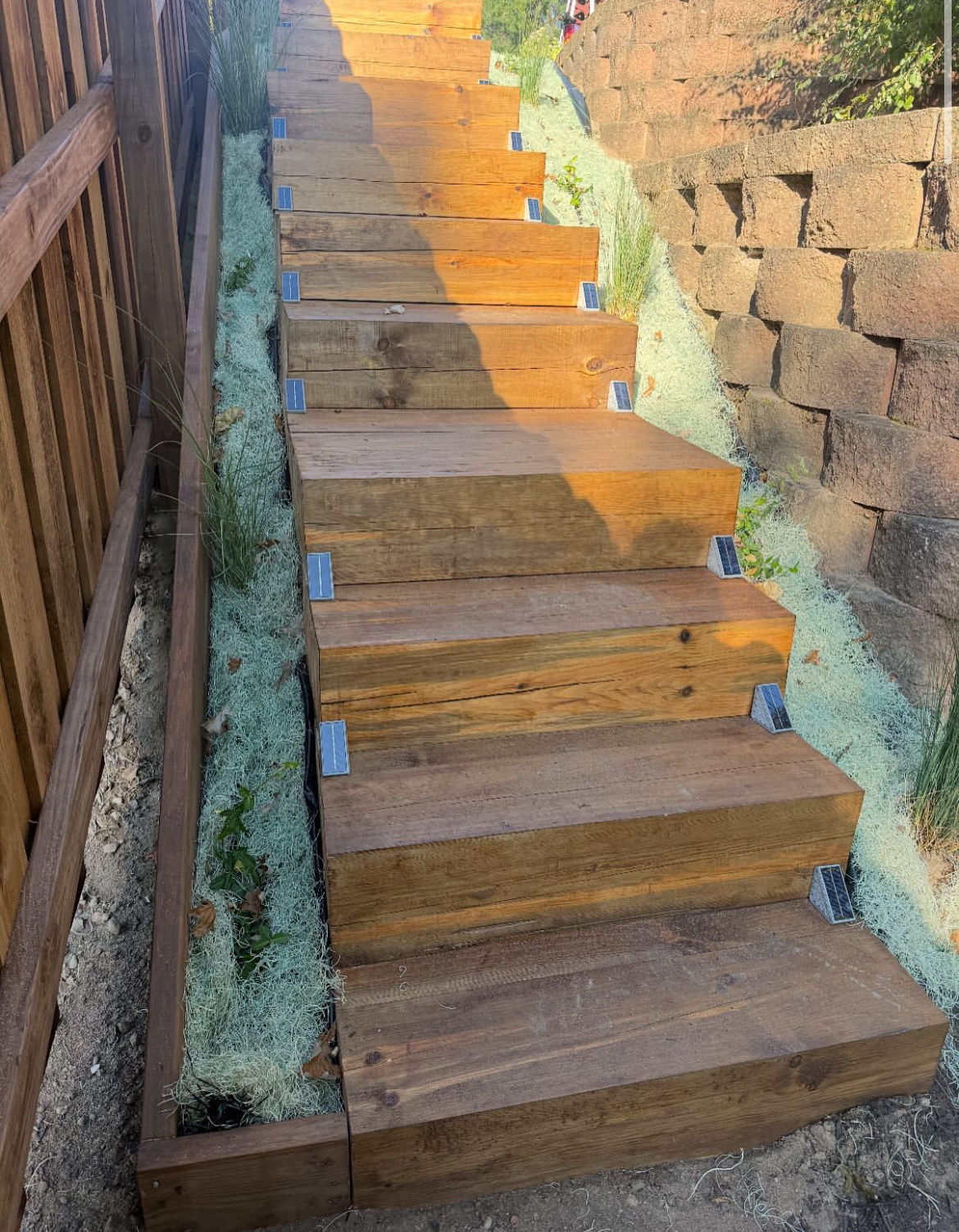 After: timber staircase with solar step lights beside a block retaining wall