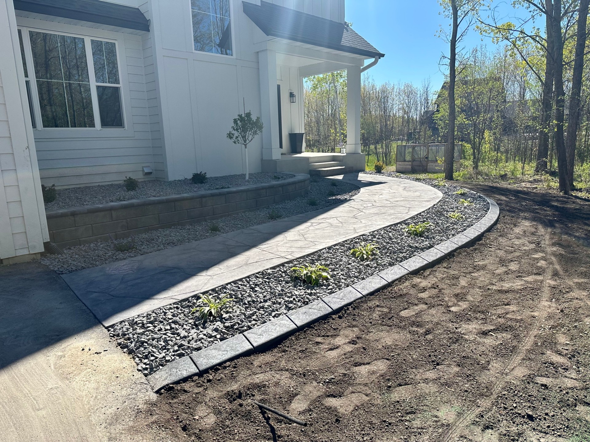 Stamped concrete walkway with retaining wall and landscape beds